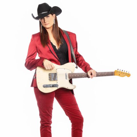 Terri Clark is in a red suit with holding a guitar.